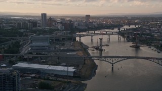 AX54_054 - Aerial stock footage of 5K aerial  video tilt from Willamette River, reveal bridges and Downtown Portland, Oregon, sunset