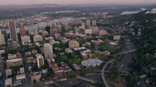 AX54_079 - 5K aerial stock footage of flying by skyscrapers and Portland State University in Downtown Portland, Oregon, sunset