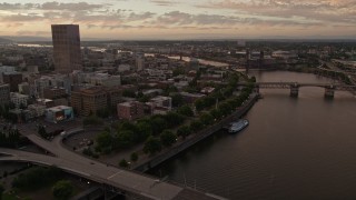 AX54_106E - 5K aerial stock footage follow the Willamette River toward the White Stag Sign in Downtown Portland, Oregon, sunset