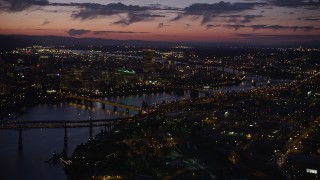 AX55_014E - 5K aerial stock footage of flying by the city and the Willamette River, seen from near Morrison Bridge, Downtown Portland, Oregon, twilight