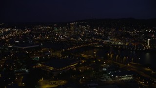 AX55_025E - 5K aerial stock footage of crossing Willamette River and Broadway Bridge, approach US Bancorp Tower, Downtown Portland, night