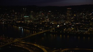 AX55_038E - 5K aerial stock footage of following Burnside Street Bridge, approaching Downtown Portland, Oregon, night