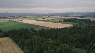 AX56_001E - 5K aerial stock footage fly over crop fields to approach a farm in Hillsboro, Oregon