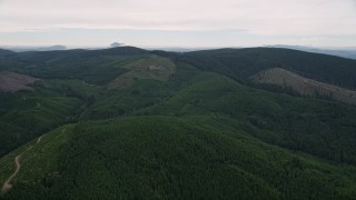 AX56_032 - 5K aerial stock footage fly over forest to approach a hillside clear cut area in Washington County, Oregon