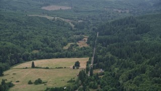 AX56_038 - 5K aerial stock footage of country road between farms and evergreen trees in Clatsop County, Oregon