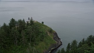AX56_097 - 5K aerial stock footage of reverse view of steep cliffs and the Cape Disappointment Light, Washington
