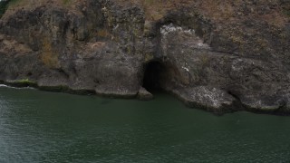 AX56_101 - 5K aerial stock footage track a cave at the base of a cliff, Cape Disappointment, Washington