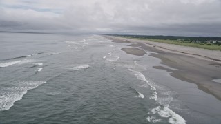 AX56_132 - 5K aerial stock footage fly over waves rolling in near a beachgoer on the sand in Seaview, Washington