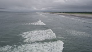AX56_138E - 5K aerial stock footage fly low over ocean waves and an empty beach in Long Beach, Washington