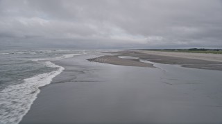 AX56_142 - 5K aerial stock footage of waves rolling into an empty beach, and seagulls taking flight in Long Beach, Washington