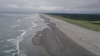AX56_143 - 5K aerial stock footage fly over ocean waves and a lone person walking the beach in Oceanside, Washington