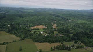 AX57_018 - 5K aerial stock footage fly over farm fields to approach a small farm and evergreen forest in Satsop, Washington