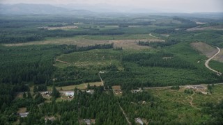 AX57_028 - 5K aerial stock footage of rural homes and a country road beside logging areas in Mason County, Washington