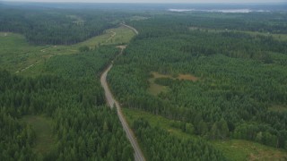 AX58_015 - 5K aerial stock footage of two lane road through evergreen forest and logging areas in Grapeview, Washington