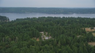 AX58_052 - 5K aerial stock footage fly over rural homes in an evergreen forest, and approach Colvos Passage, Olalla, Washington