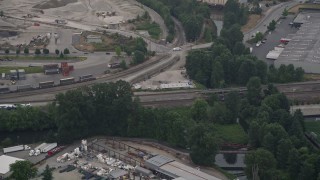 AX58_077E - 5K aerial stock footage of tracking a commuter train running beneath a freeway in Tukwila, Washington
