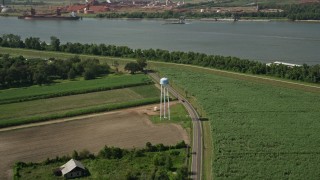 AX60_030 - 5K aerial stock footage of a water tower beside a country road and crop fields in Wallace, Louisiana