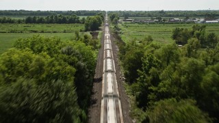 AX60_060 - 5K stock footage aerial video follow railroad tracks to approach and fly over a train in Vacherie, Louisiana