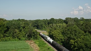 AX60_064 - 5K aerial stock footage track a train traveling past sugar cane fields and over a country road in Vacherie, Louisiana