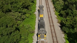 AX60_066 - 5K aerial stock footage tilt and track the engine of a train running between trees in Edgard, Louisiana