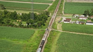 AX60_070 - 5K aerial stock footage of tracking a train speeding past rural homes and sugar cane fields, Edgard, Louisiana