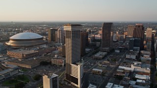 AX61_026E - 5K aerial stock footage flyby downtown and Plaza Tower to approach Superdome and New Orleans Arena at sunset, New Orleans, Louisiana