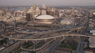 AX61_029 - 5K aerial stock footage reverse view of Superdome and Downtown New Orleans skyscrapers at sunset, Louisiana
