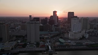 AX61_064 - 5K aerial stock footage pass riverfront hotels and skyscrapers in Downtown New Orleans with the setting sun in the background, Louisiana