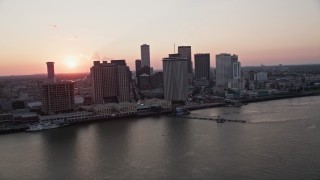 AX61_066 - 5K aerial stock footage of the setting sun behind Downtown New Orleans skyscrapers, Louisiana