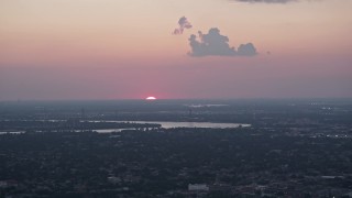 AX61_078 - 5K aerial stock footage of the setting sun dipping below the horizon beyond the Mississippi River and Carrollton, Louisiana