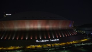 AX62_001 - 5K aerial stock footage of ascending from the Mercedes-Benz Superdome at night, New Orleans, Louisiana