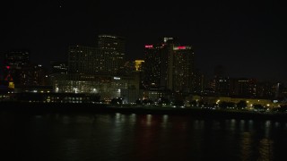 AX62_031 - 5K aerial stock footage of low altitude view of riverfront skyscrapers in Downtown New Orleans at night, Louisiana