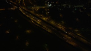 AX62_049 - 5K aerial stock footage of reverse and bird's eye view of freeway interchange at night, New Orleans, Louisiana