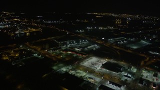 AX62_050 - 5K aerial stock footage reverse view of a strip mall by the Danziger and I-10 High Rise Bridges at night, New Orleans, Louisiana