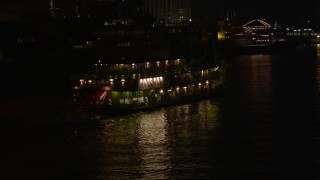 AX63_007E - 5K aerial stock footage of tracking Natchez Steamboat on Mississippi River at night, French Quarter, New Orleans, Louisiana