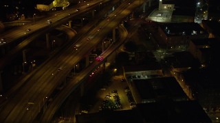 AX63_012 - 5K stock footage aerial video track an ambulance exiting the Crescent City Connection Bridge at night, New Orleans, Louisiana