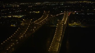 AX63_015E - 5K aerial stock footage orbit top of Crescent City Connection Bridge at night to reveal Downtown New Orleans, Louisiana