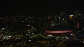 AX63_022 - 5K aerial stock footage of lighting change at the Superdome near Downtown New Orleans skyscrapers at night, Louisiana