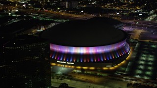 AX63_024 - 5K aerial stock footage of orbiting the Superdome as the lights change colors at night, Downtown New Orleans, Louisiana