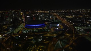 AX63_039E - 5K aerial stock footage follow Interstate 10 to the interchange and the Superdome at night in Downtown New Orleans, Louisiana
