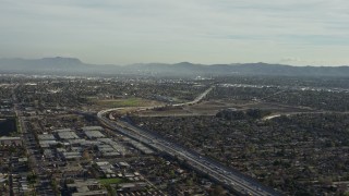 AX64_0001 - 5K aerial stock footage of I-5 / 170 split by warehouse buildings and suburban homes in Pacoima, California