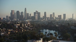 AX64_0078E - 5K aerial stock footage of an approach to Echo Park and hazy Downtown Los Angeles skyline, California