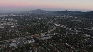 AX64_0155 - 5K aerial stock footage approach residential neighborhoods beside Tujunga Wash, Valley Village, California, twilight
