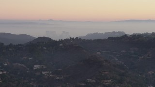 AX64_0156 - 5K aerial stock footage of Century City behind hilltop mansions in Hollywood Hills, California, twilight