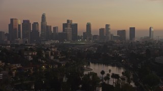 AX64_0181E - 5K aerial stock footage of Downtown Los Angeles in haze seen from Echo Lake at twilight, California
