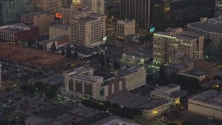 AX64_0200 - 5K aerial stock footage track a police helicopter flying over office buildings in Downtown Los Angeles, California, twilight