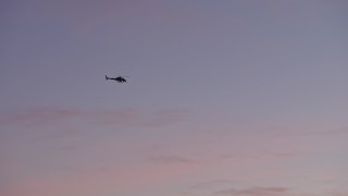 AX64_0203 - 5K aerial stock footage of a police helicopter in the sky, Los Angeles, California, twilight
