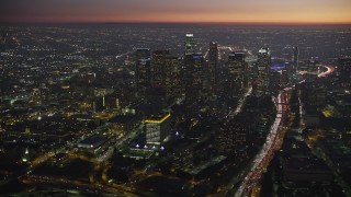AX64_0263E - 5K aerial stock footage of tall skyscrapers and Highway 110 in Downtown Los Angeles, California at twilight