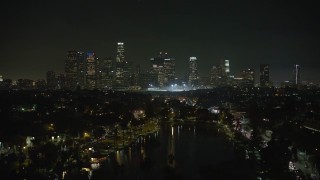 AX64_0351E - 5K aerial stock footage fly over Echo Lake to approach Downtown Los Angeles skyline at night, California
