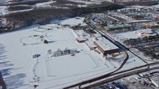 AX66_0002E - 4.8K aerial stock footage of a snow covered sports field at the State University of New York at Farmingdale, Long Island